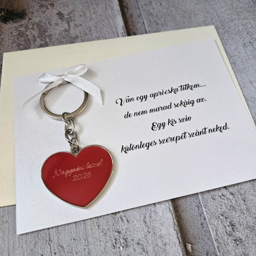 Szív alakú gravírozott fém kulcstartó egyedi masnival díszített A5-ös méretű ajándékkártyán elegáns színes borítékkal – kreatív keresztszülő felkérő és esküvői szülőköszöntő ajándék